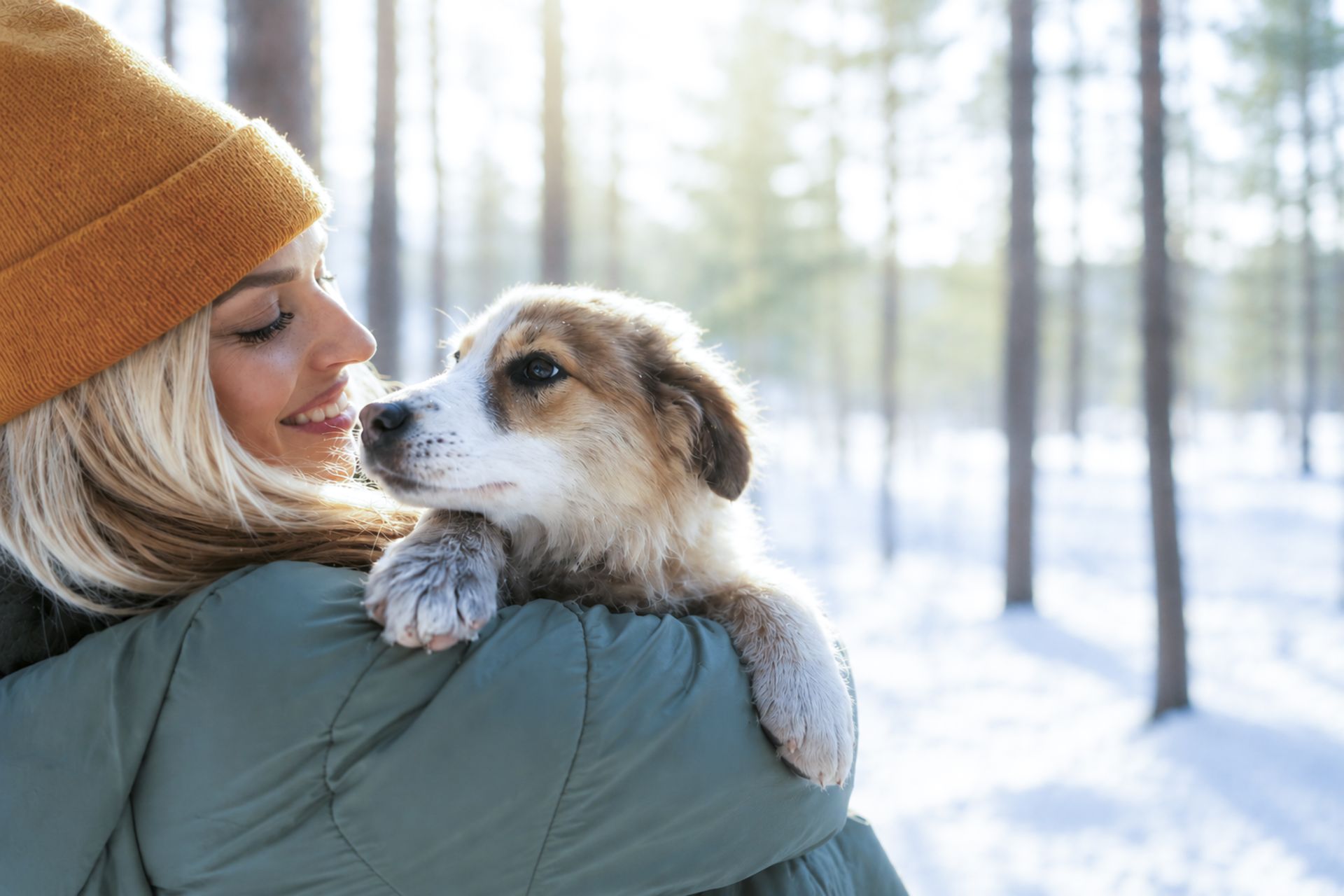 Woman holding puppy in snowy forest, representing holistic pet wellness